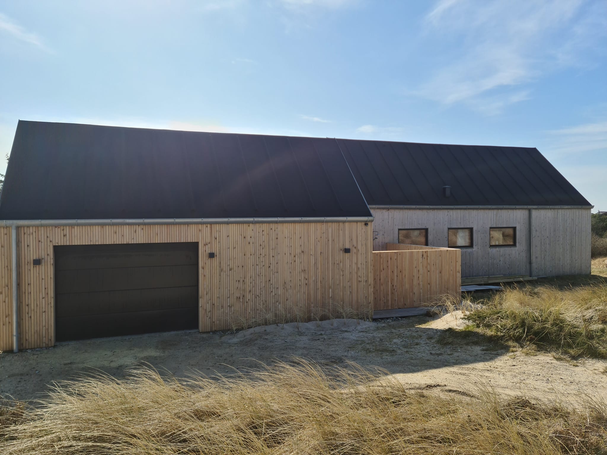 Moderne træhus med sort tag ved kysten