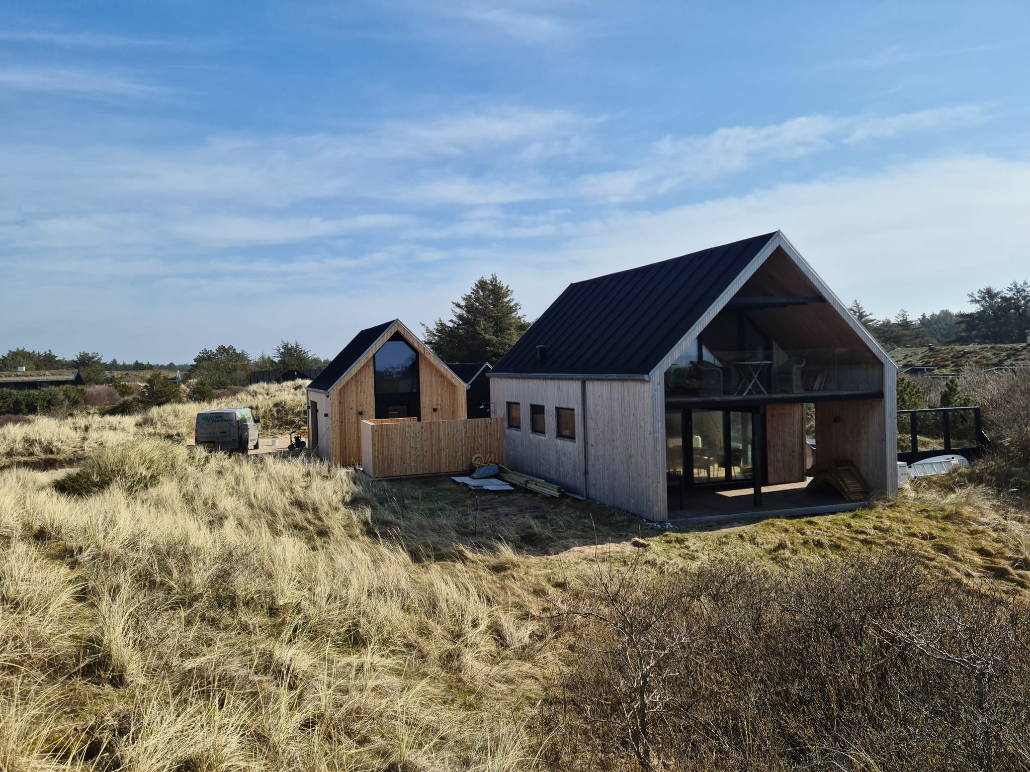 Moderne sommerhus i klitlandskab under blå himmel